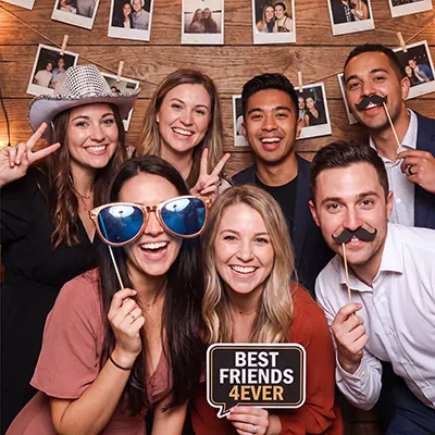 Friends with props and sunglasses at a party photo booth